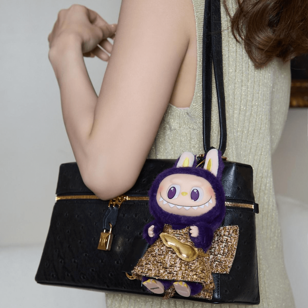 A fluffy Labubu doll with bunny ears attached to a stylish purse
